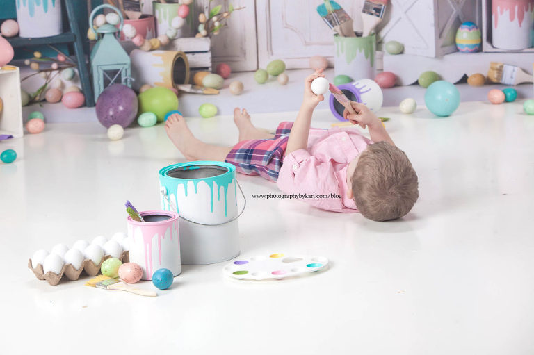 Easter portrait of boy in a pink shirt painting an egg