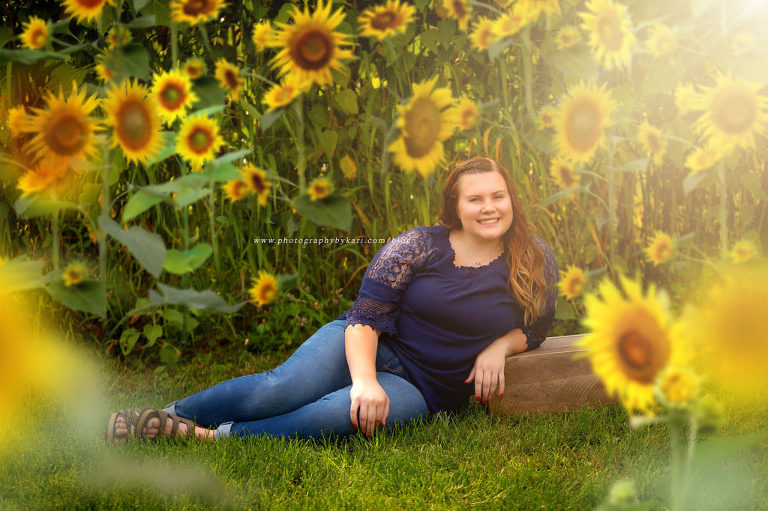 senior girl sitting in front of sunflowers