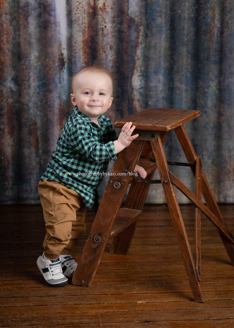One year old baby boy standing by ladder