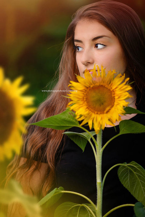 Senior girl portrait with sunflower by face
