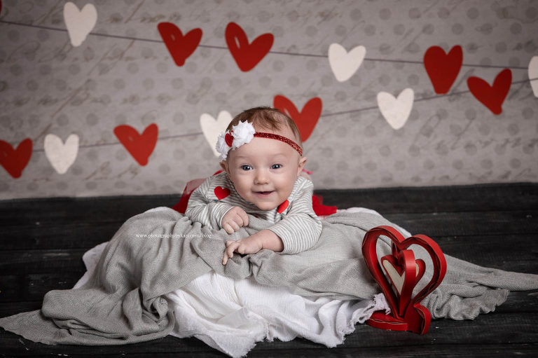 3 month old baby laying with hearts as a background