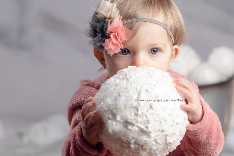 one year old girl with snowball by face