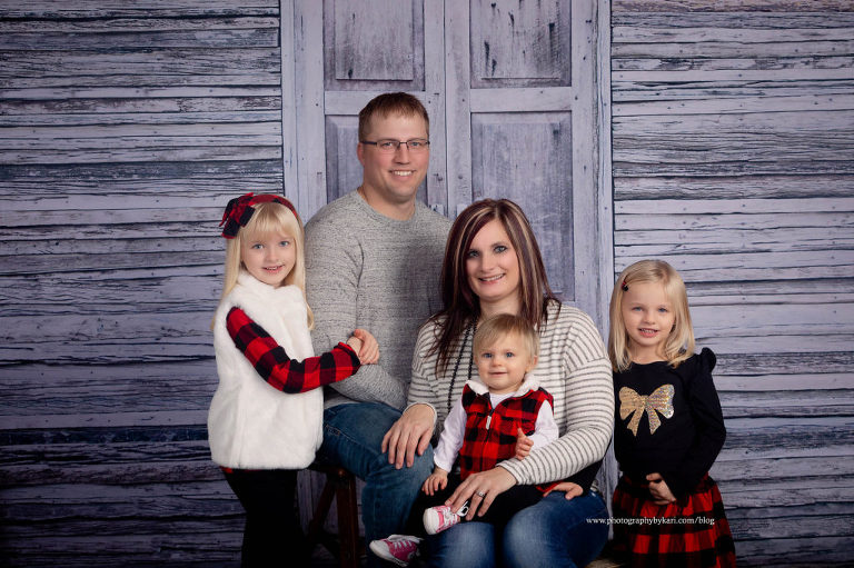 Family of 5 with black and red plaid on wood background