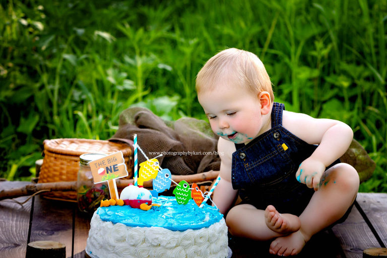 baby boy in overalls looking at fishing cake