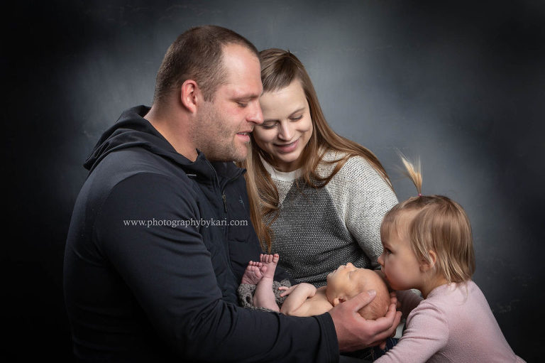 family newborn portrait with sister kissing baby taken in the Photography by Kari studio