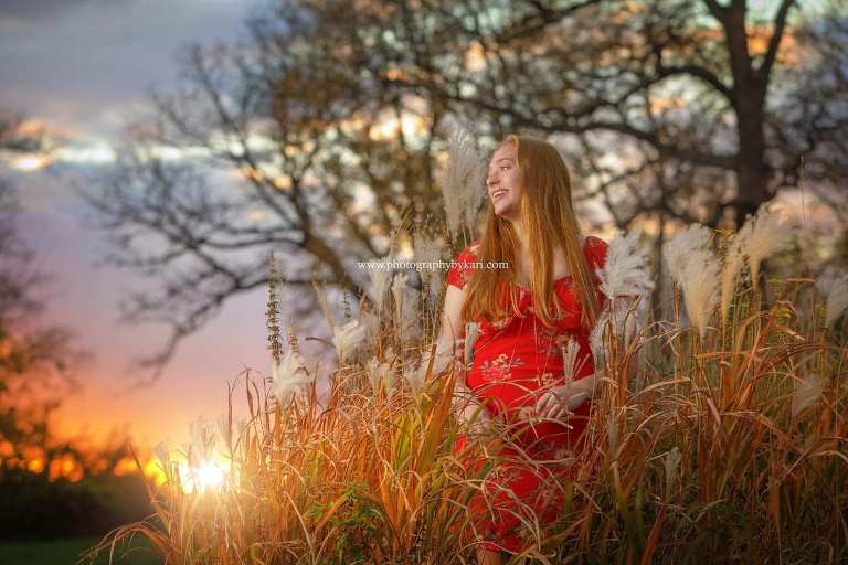mn senior girl standing in grass with sun setting
