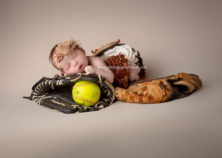 Newborn girl portrait with softball and gloves