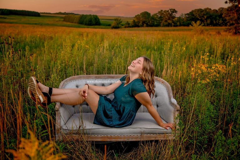 Senior girl portrait laughing on couch in field