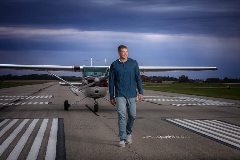 Mason walking on Preston Airport runway with his airplane MN senior pictures.