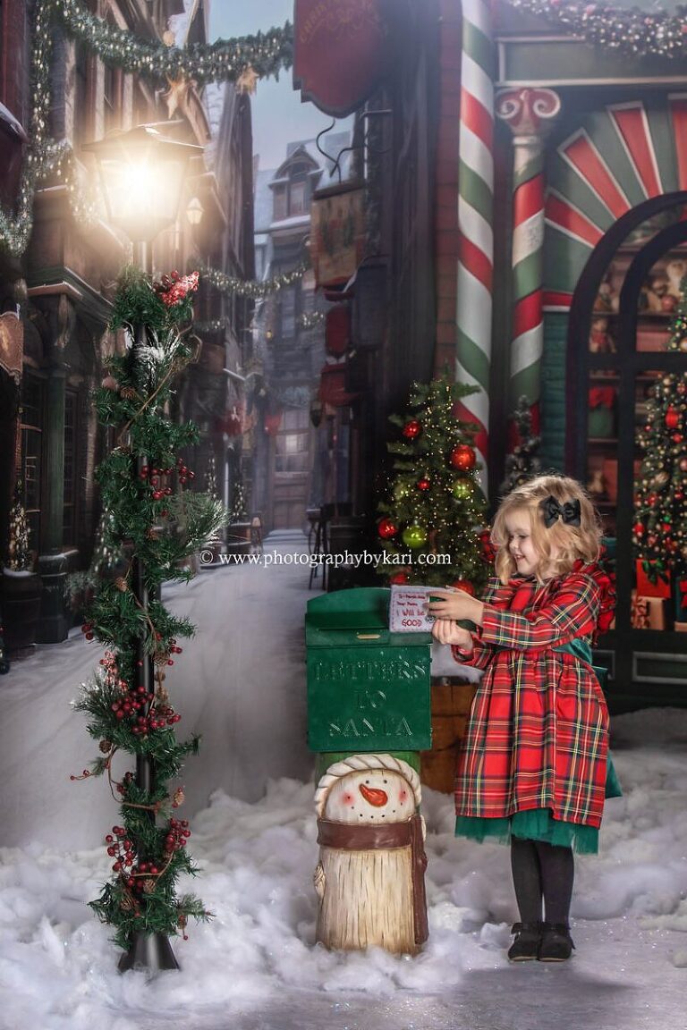 christmas mini photo of little girl wearing red and green plaid dress sending a letter to santa taken in studio by photography by kari
