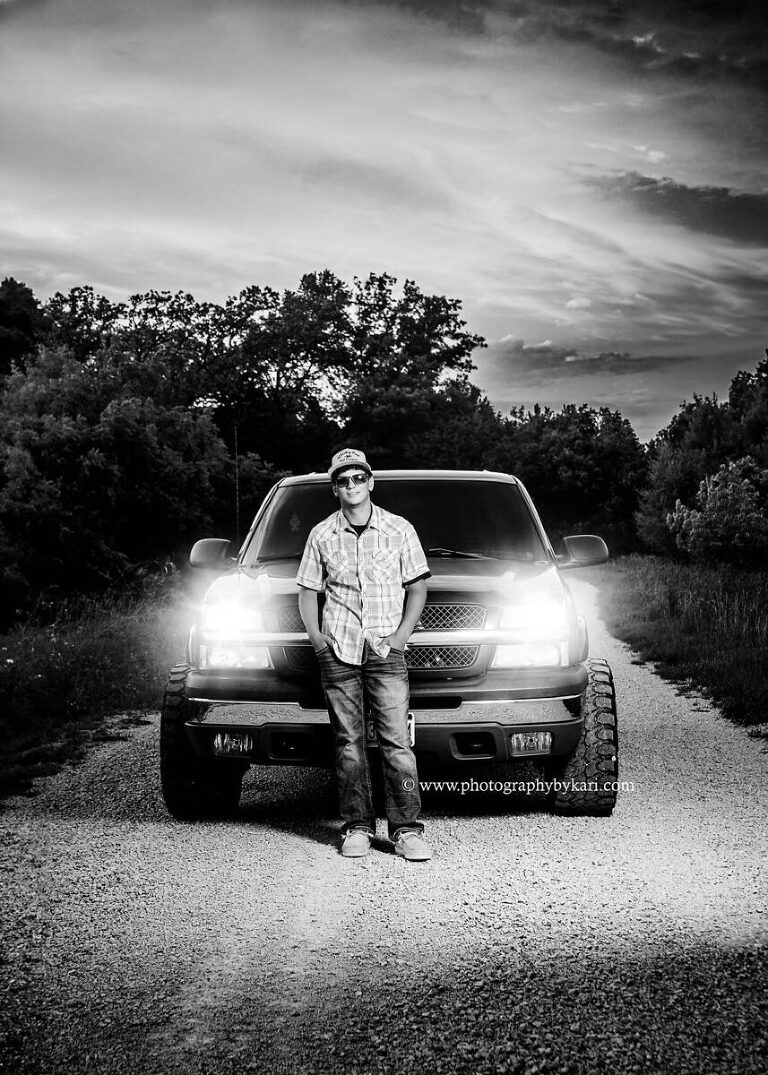 Guy Senior Portraits MN  with black truck at sunset on gravel road taken by Photography by Kari