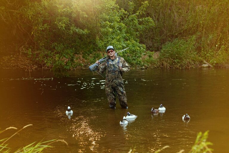 Guy Senior Portraits MN duck hunting with gun and duck decoys baken by Photography by Kari