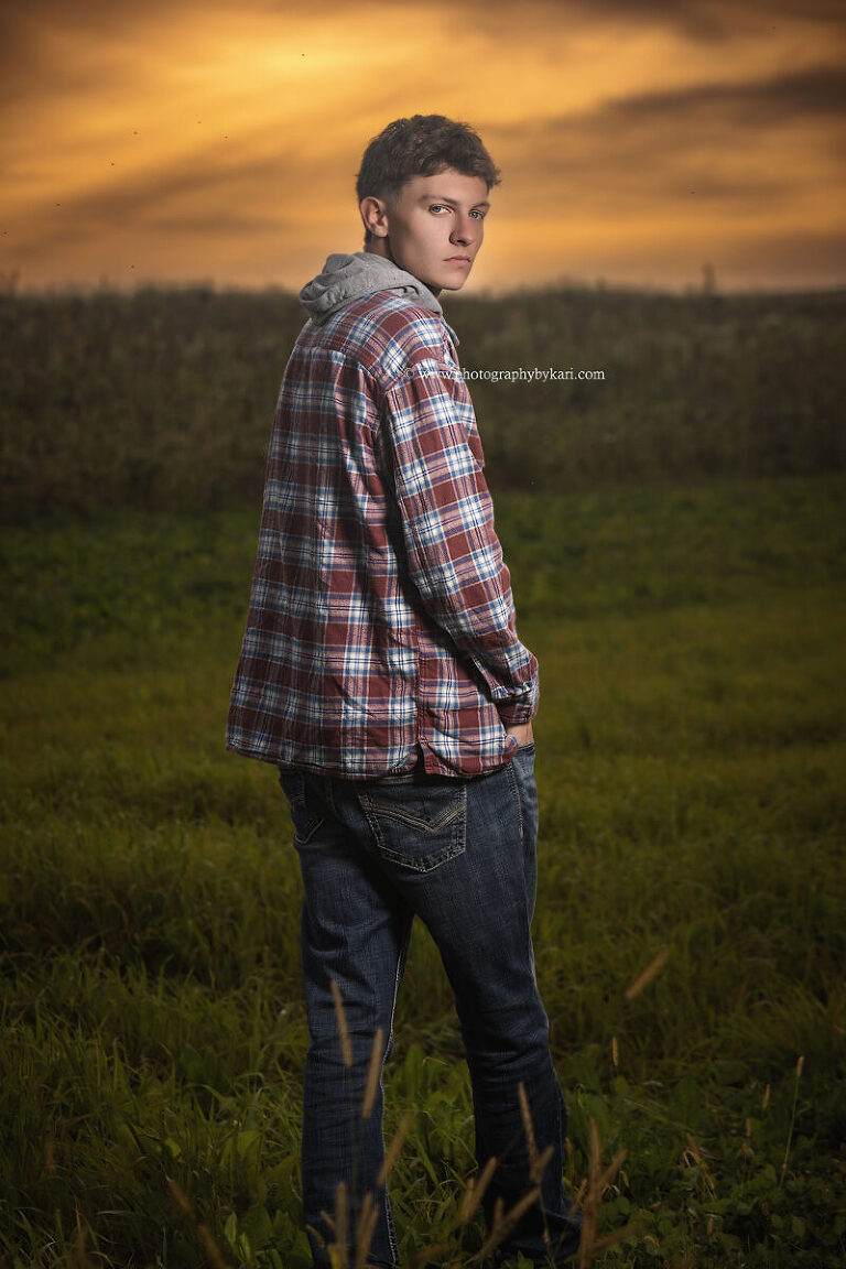 Grand Meadow senior boy standing in tall grass at sunset near Spring Valley MN