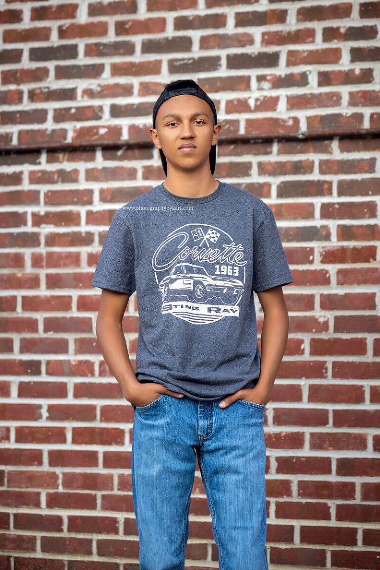 Senior boy standing against brick wall in Spring Valley MN"