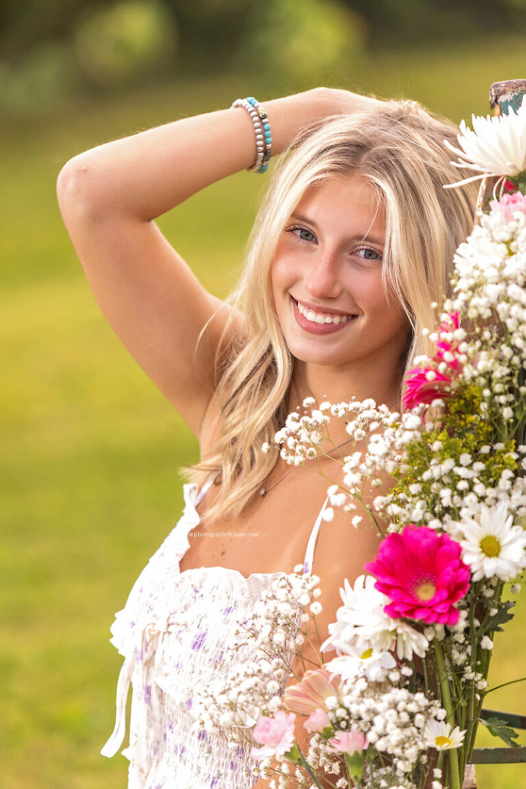 Cassie leaning on rustic ladder surrounded by wildflowers and tall grass