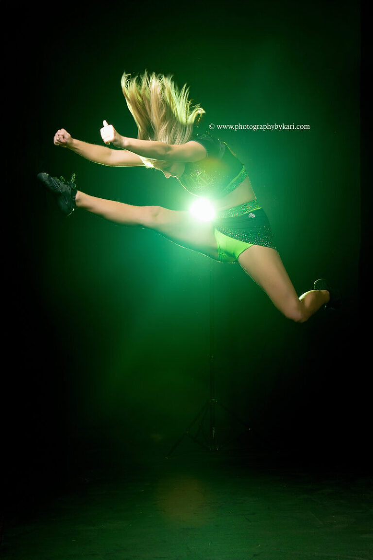 Senior girl striking cheer pose with bold lighting effects in Spring Valley, MN studio