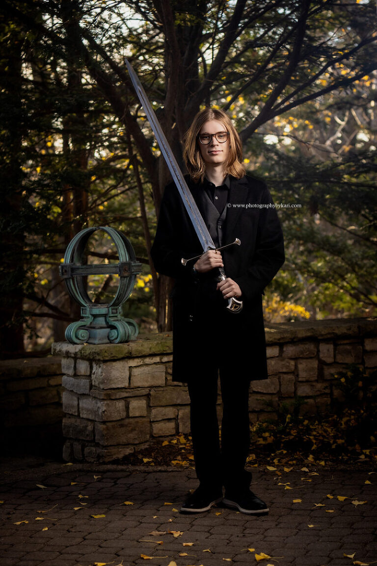 Senior boy holding sword during creative photo session at Plummer House
