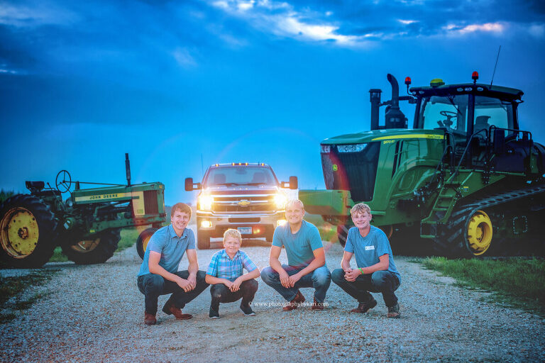 Seth and his brothers posing together on a rural road with their tractors and  truck for his  SE MN senior photo session