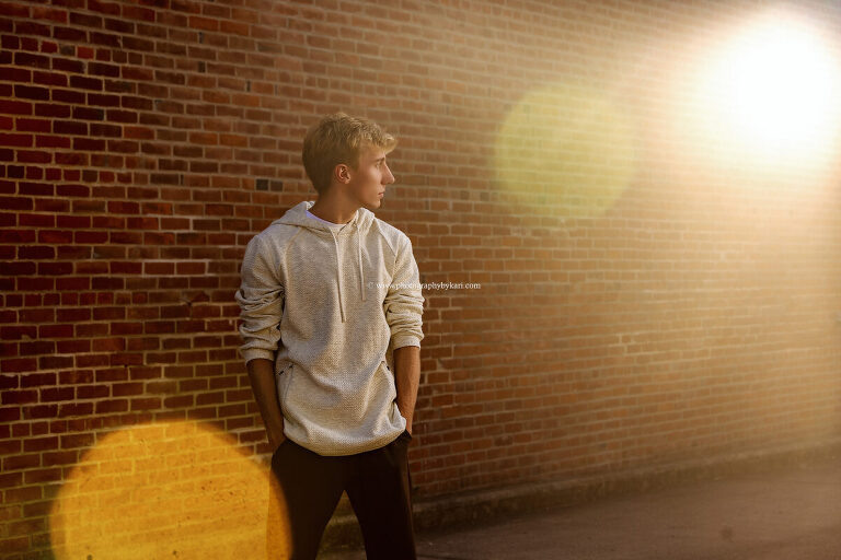 Talan posing near brick building in downtown Lanesboro for senior portraits