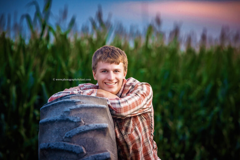 SE MN Senior boy standing by tractor on rural Minnesota farm"