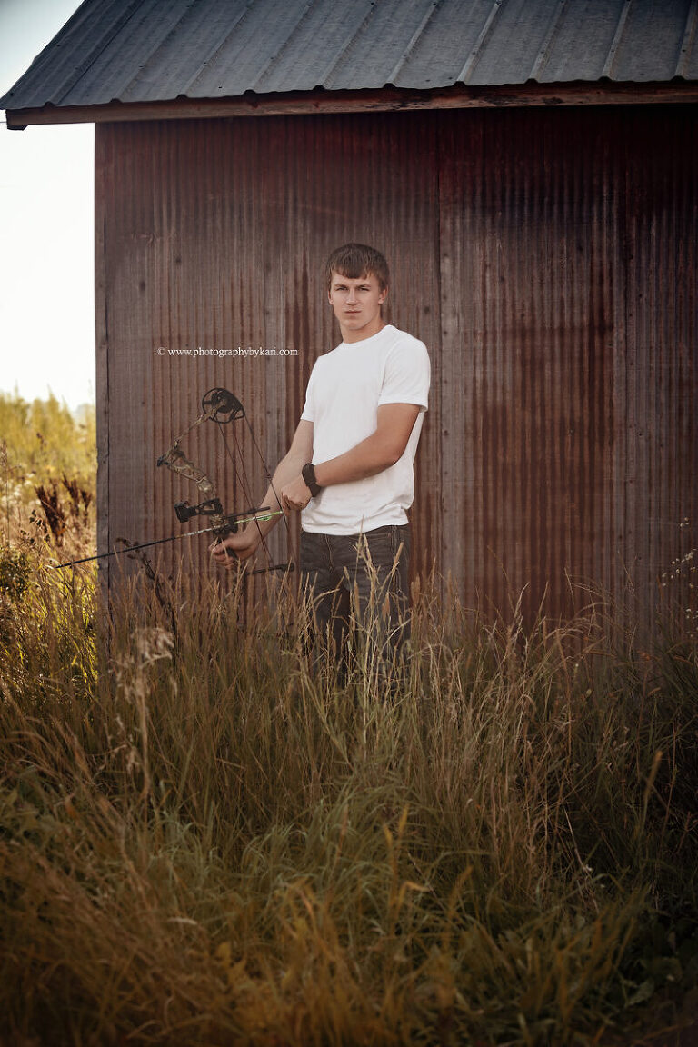 SE MN Senior boy holding hunting bow during outdoor photo session near Spring Valley MN