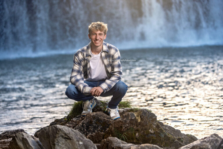 Senior boy squatting near Lanesboro Stone Dam for outdoor portrait