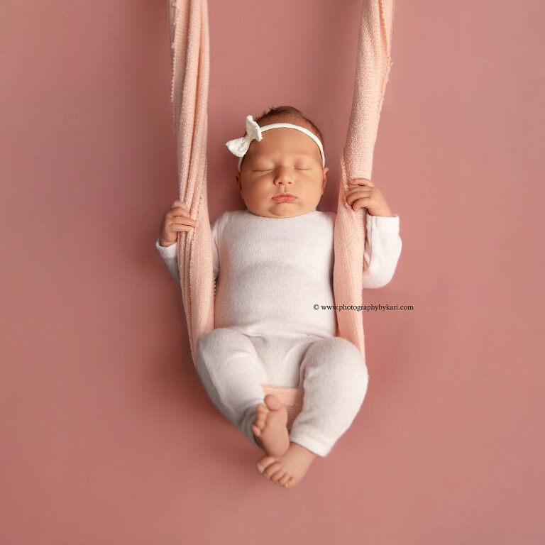 Newborn girl portrait with pink tones and delicate headband in Spring Valley MN photography studio