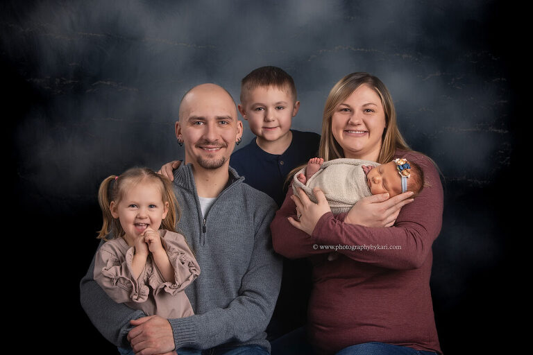 Family portrait with newborn baby girl and parents welcoming third child Minnesota photographer