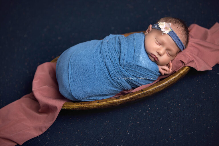 Newborn girl wrapped in blush tones posed in studio Photography by Kari Southeast MN